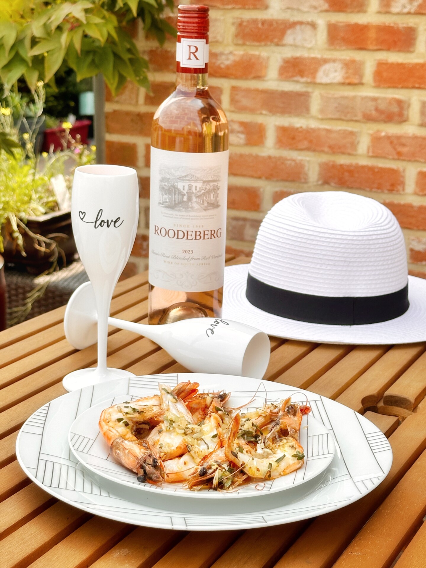 Zomer tafel met een flesje rosé wijn Roodeberg Rosé en gegrilde gamba's